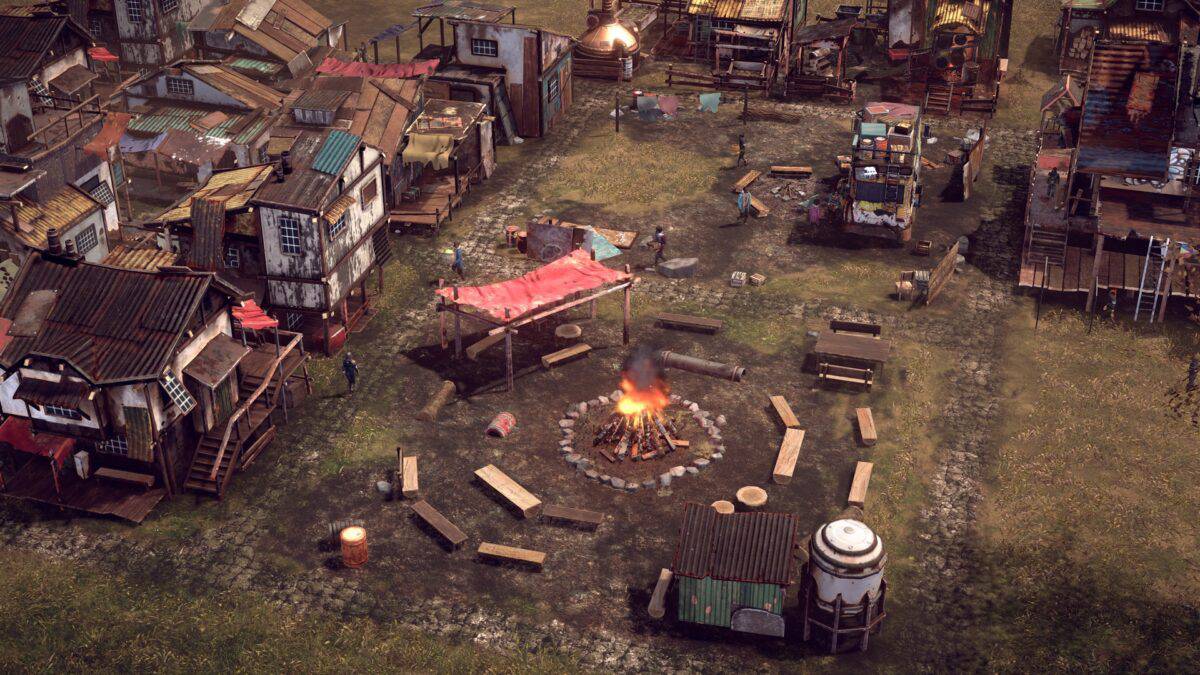 Aerial view of a rustic settlement with makeshift buildings surrounding a central fire pit, with benches and scattered items.
