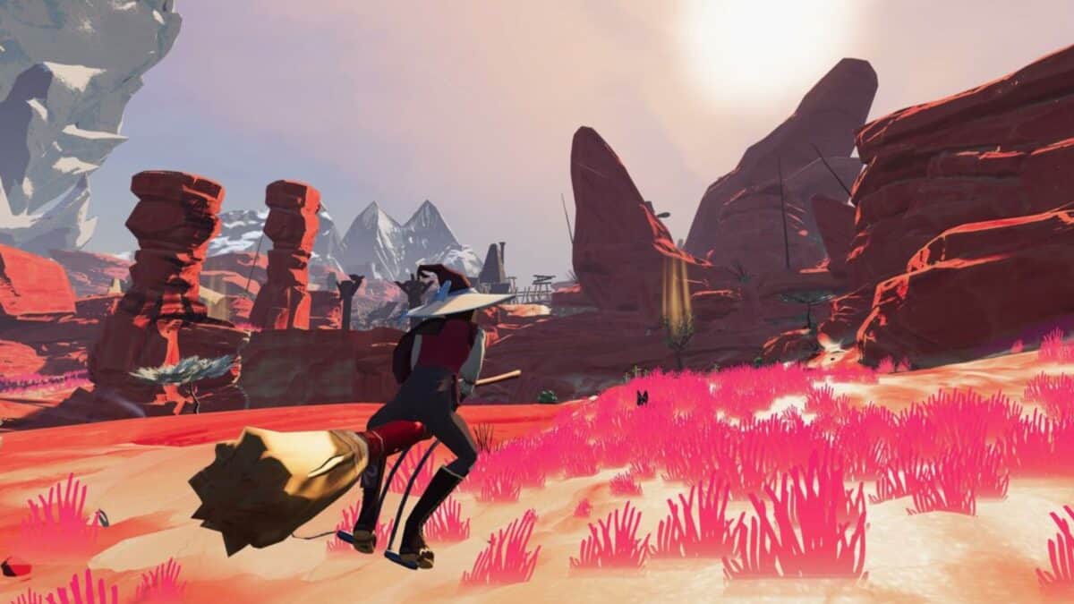 A character rides a broomstick over bright pink grass in a stylized desert landscape with rocky formations and distant mountains under a bright sky.