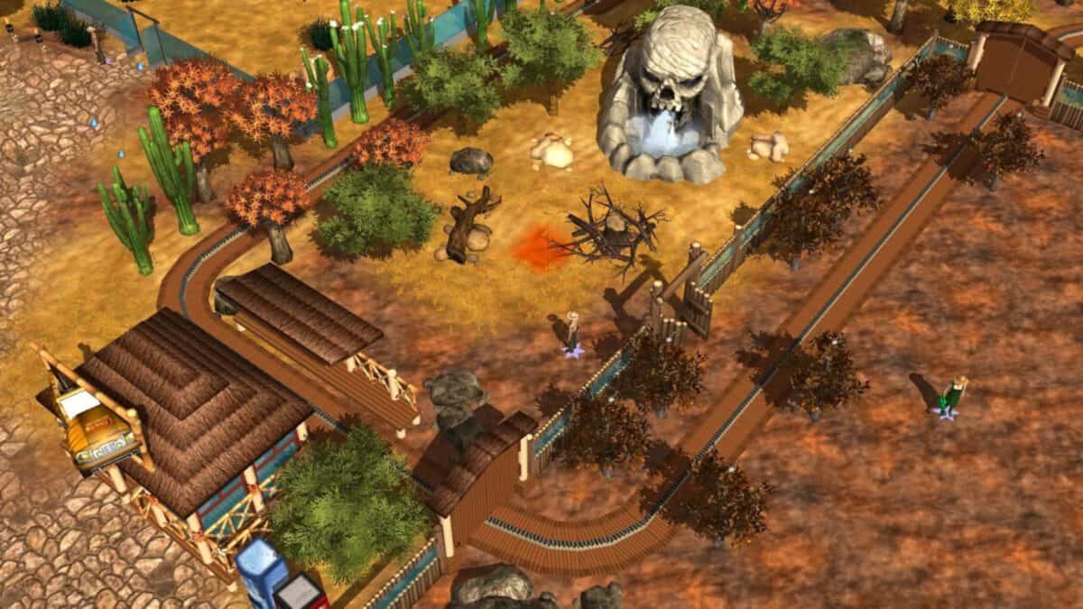 A theme park ride track winds through a desert-themed area with cacti, trees, and a large skull rock formation. A station and queue area are visible in the bottom left.