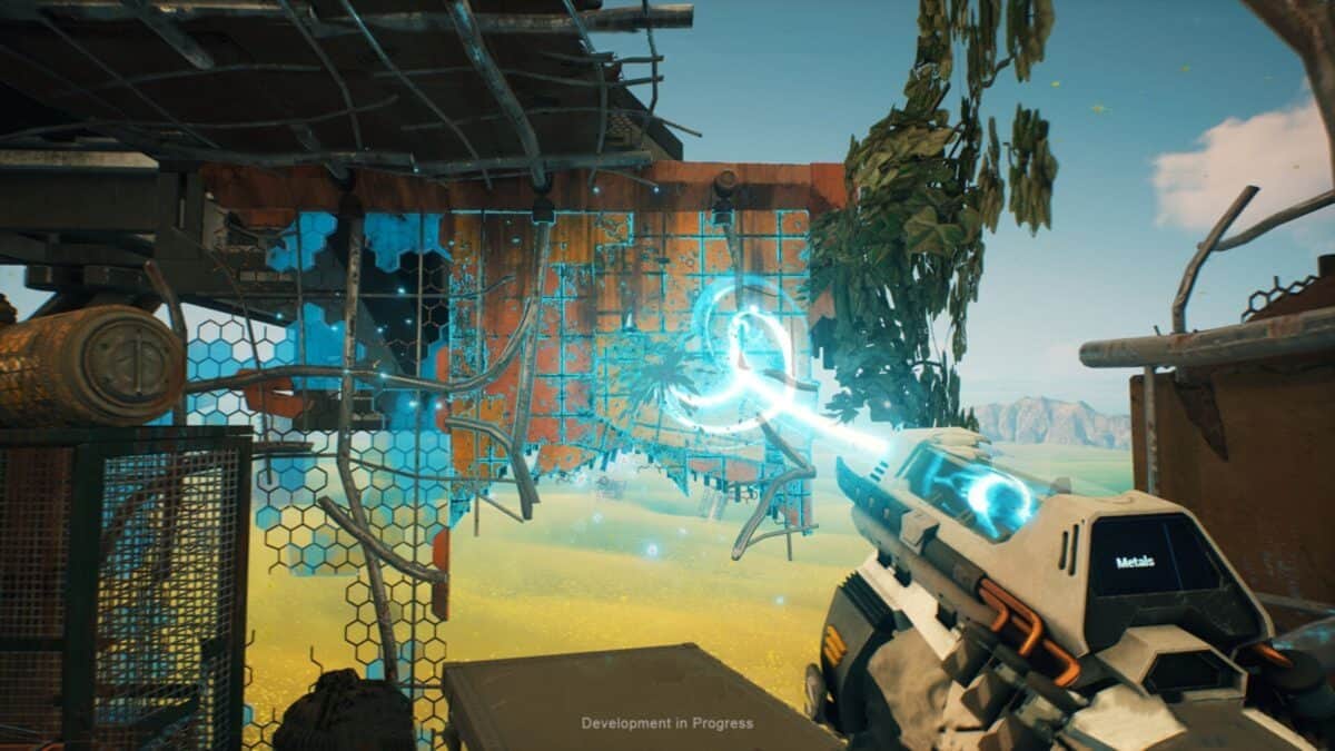 A sci-fi video game scene shows a player using a futuristic tool to repair or modify a damaged metal wall in a desert environment.