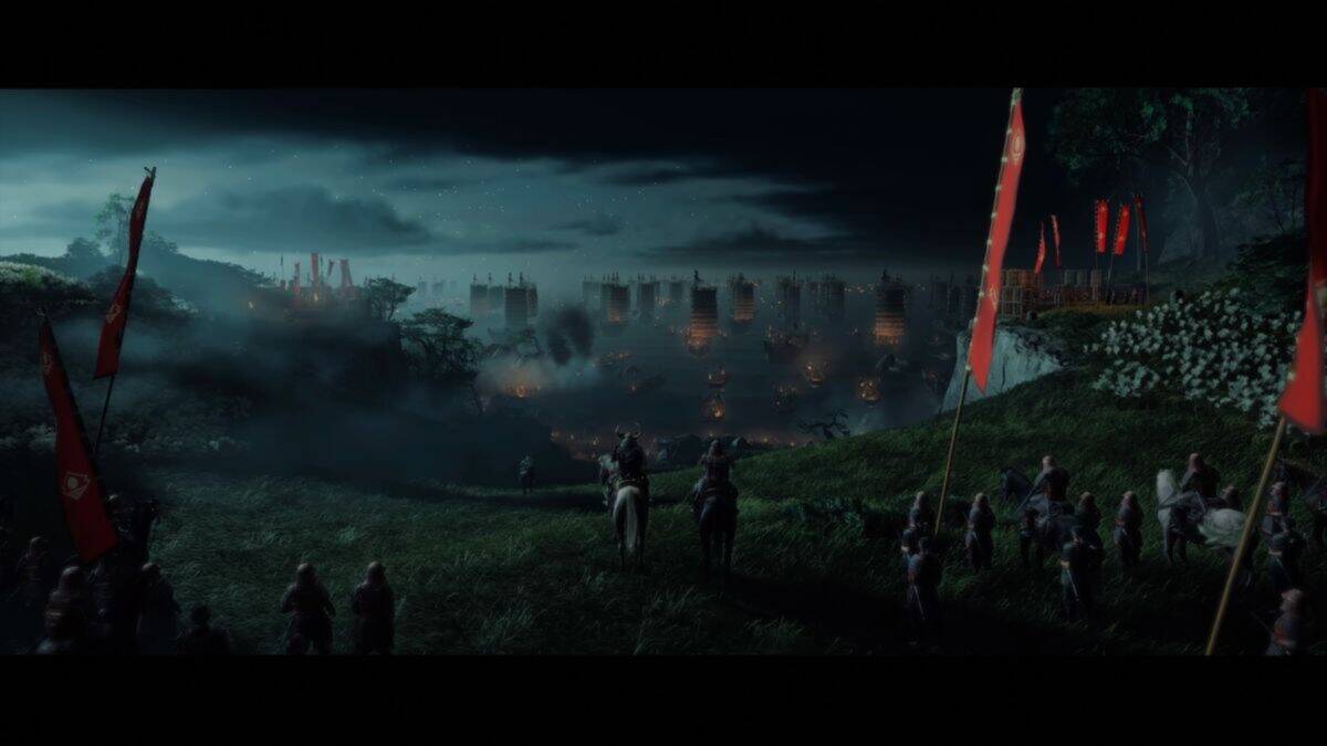A group of armored figures on horseback and on foot overlook a misty, fortified city illuminated by fires at night, with red flags visible in the foreground.
