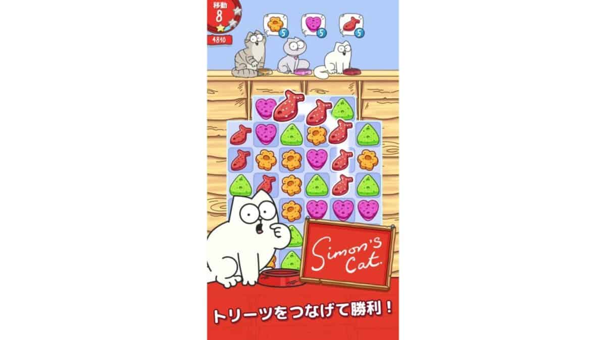 A puzzle game screen featuring Simon's Cat, colorful treat icons to match, and Japanese text at the bottom. Three cats sit on a shelf above the game grid.