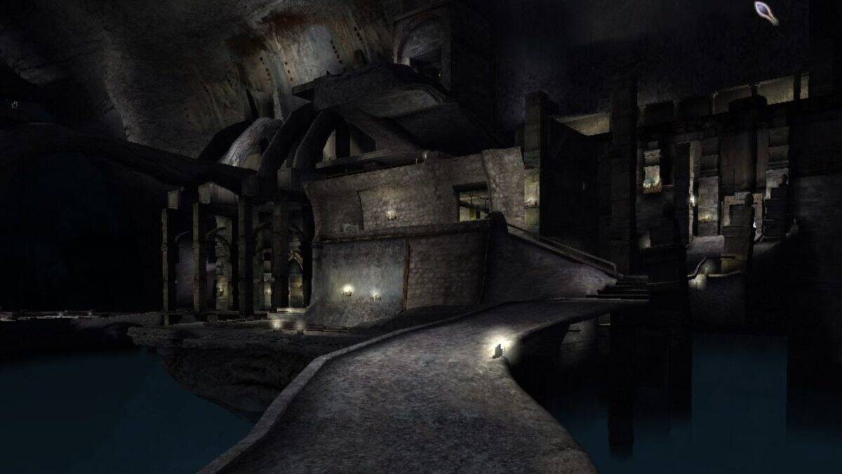 A dimly lit, stone structure with arched ceilings and walkways sits above dark water in an underground cavern.
