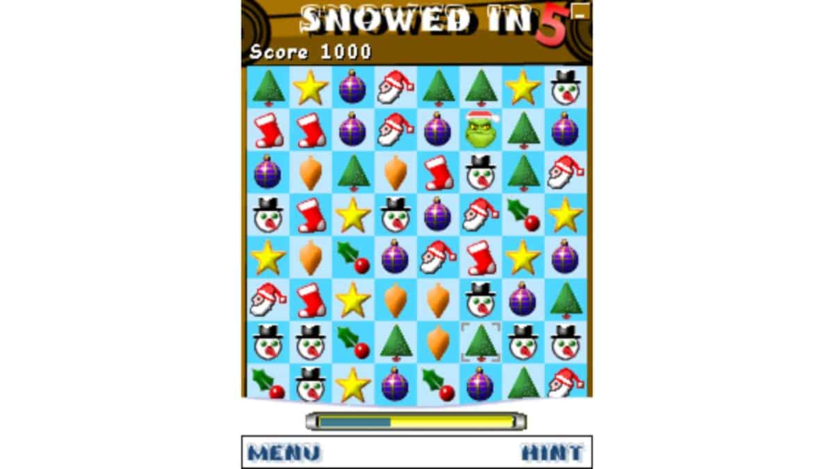 A match-three puzzle game screen with Christmas-themed icons such as trees, ornaments, stars, snowmen, stockings, and hats; score is 1000, game title reads "Snowed In 5".