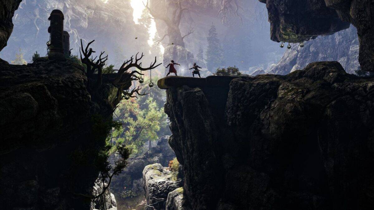 Two figures stand on a rocky ledge in a mountainous, forested landscape with dramatic lighting and rugged terrain.
