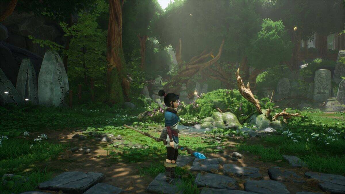 A character holding a staff stands in a lush, sunlit forest clearing with large stones and fallen branches scattered around.