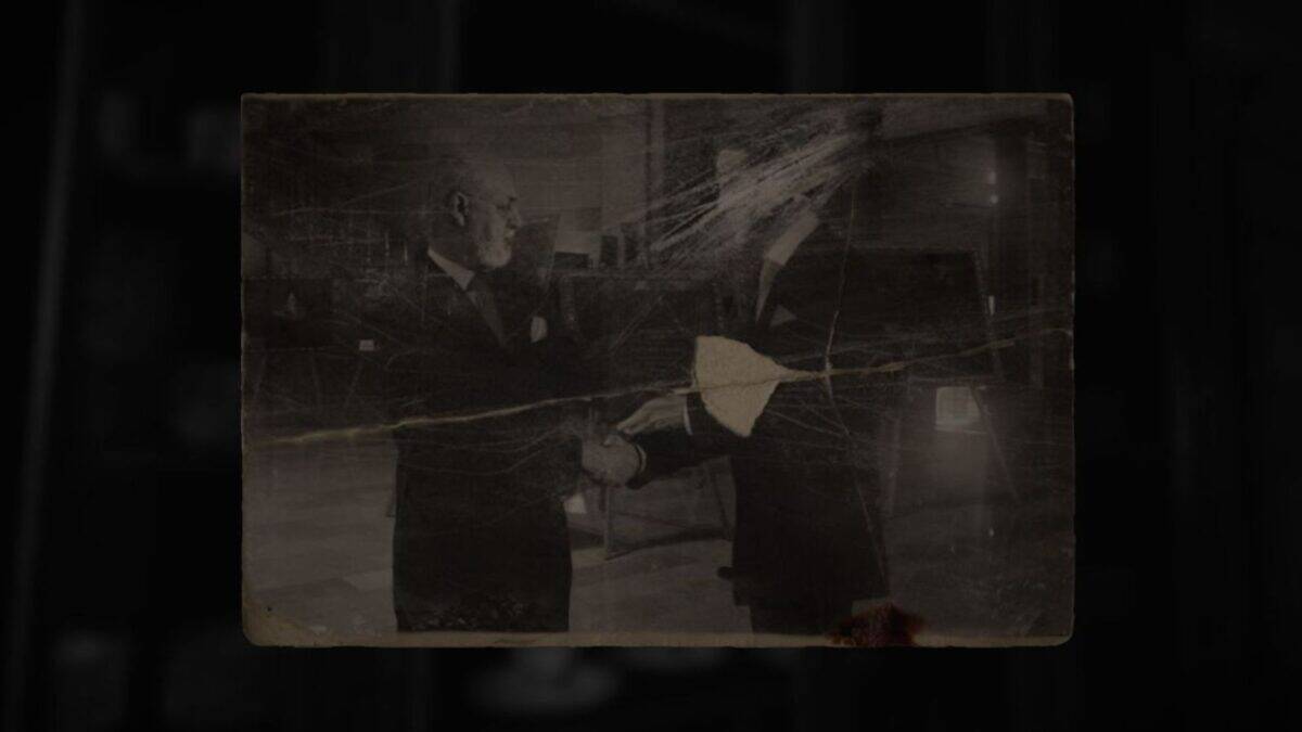 A worn, scratched black-and-white photo shows two men in suits shaking hands. One man’s face is partially obscured by damage to the photo.
