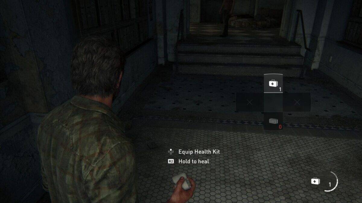 A video game character holds a health kit in a dimly lit hallway, with on-screen prompts displaying how to equip and use the kit.